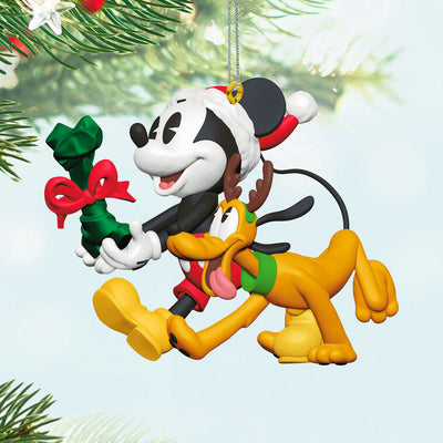 Mickey Mouse holding a dog bone gift walks beside Pluto in reindeer antlers in this cheerful Disney Hallmark Christmas ornament.