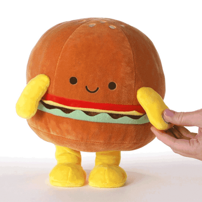 Smiling plush hamburger toy with sesame seed bun, lettuce, tomato, cheese layers, dances and plays a parody of 'Girls Just Wanna Have Fun.
