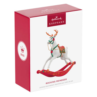 White reindeer Christmas ornament with bronze antlers and hooves, red flower accents, green bridle, on rocking stand

