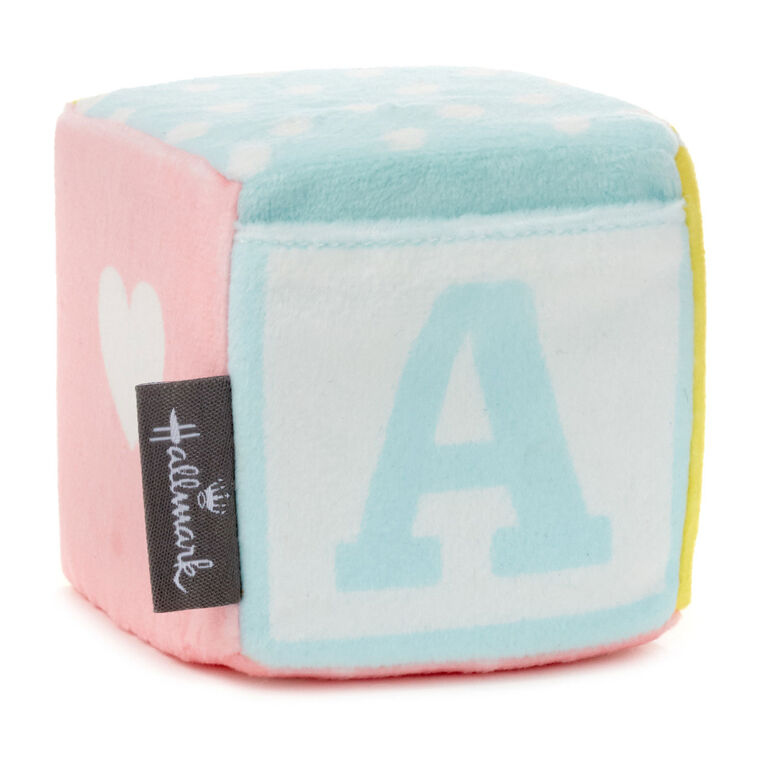 Pastel plush baby block with ABC design and pocket for holding a gift card or mini greeting card, featuring a rattle inside.
