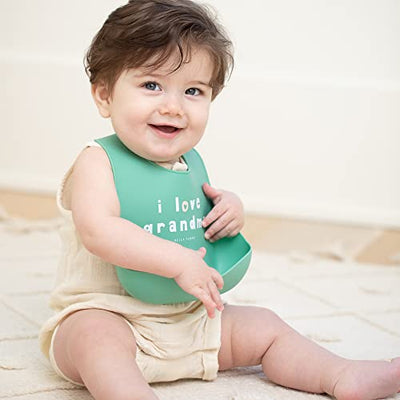 Pink silicone baby bib with “Love Grandma” phrase, features deep food-catching pocket and adjustable neck.

