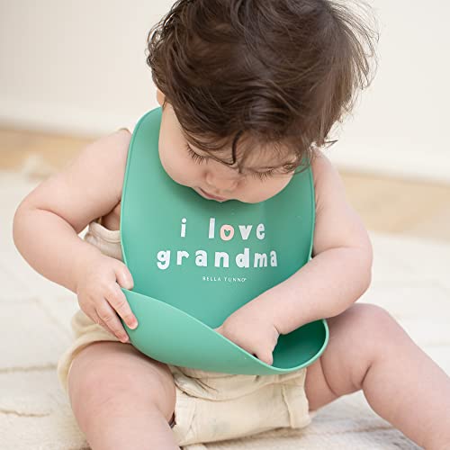 Pink silicone baby bib with “Love Grandma” phrase, features deep food-catching pocket and adjustable neck.

