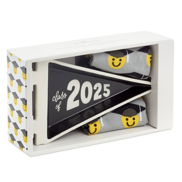 Class of 2025 black-and-white trinket tray with matching socks featuring smiley faces in graduation caps.

