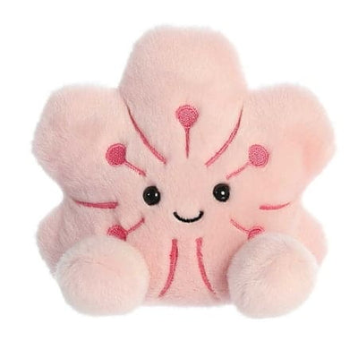 A pink plush flower toy with a smiling face. The flower has a yellow center and several pink fabric layers.