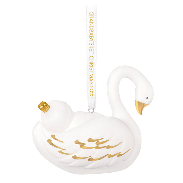 Porcelain Christmas ornament of a baby nestled in a swan’s wings, with gold accents and a commemorative 2025 ribbon

