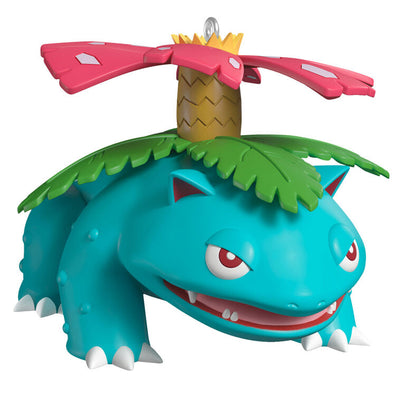 Hallmark Keepsake Pokémon Venusaur ornament with pink blossom on its back, blue-green body, red eyes, and festive Christmas style.