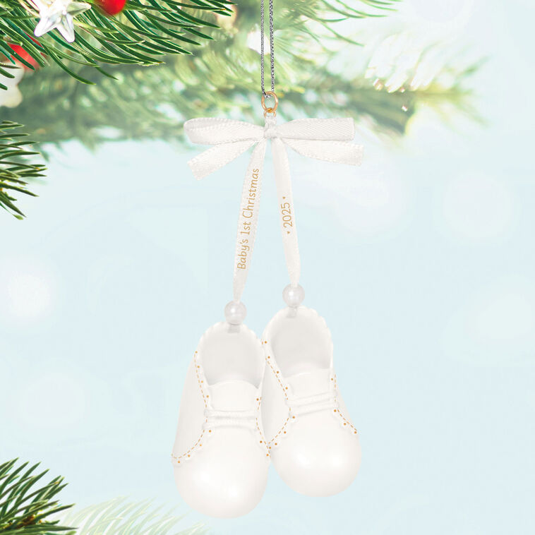 White porcelain baby booties ornament with 14K gold accents and satin ribbon bow, marked for baby’s 1st Christmas 2025.