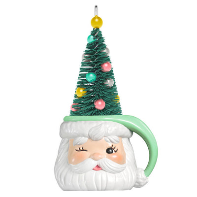 Green stocking hat mug ornament with winking Santa face and pastel ball-decorated bottlebrush tree inside

