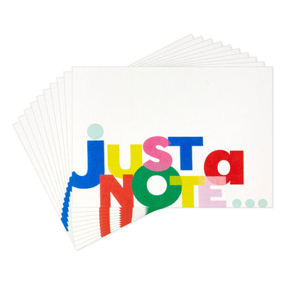 White note cards with playful block-style multicolor “Just a Note” lettering, bundled in kraft paper wrap.
