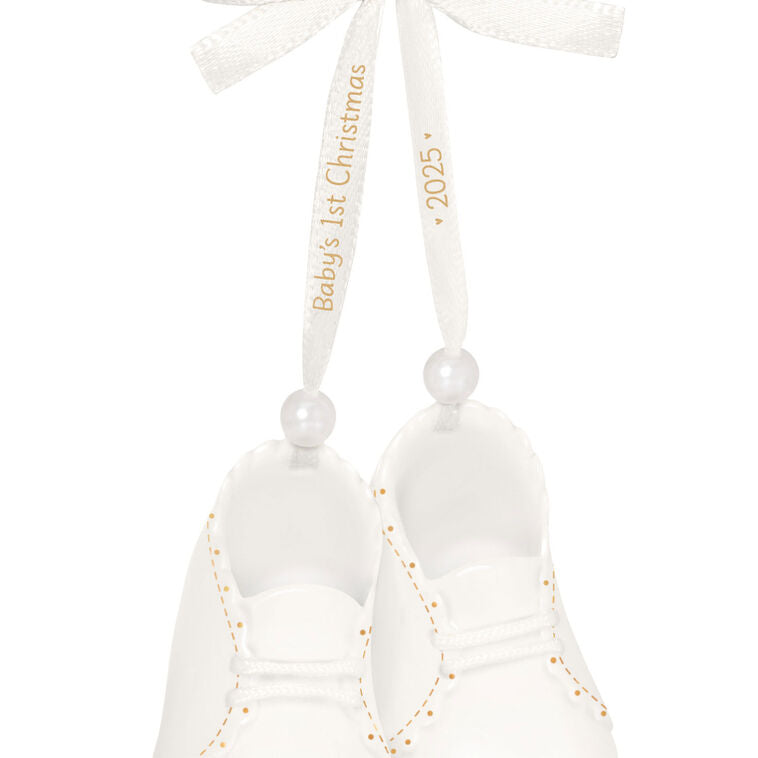 White porcelain baby booties ornament with 14K gold accents and satin ribbon bow, marked for baby’s 1st Christmas 2025.