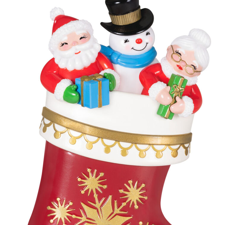 Hallmark Keepsake Stocking Stuffers ornament—red and white stocking with gold snowflakes, Santa, Mrs. Claus, and snowman in vintage style
