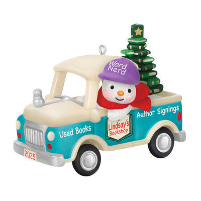 Hallmark Keepsake Holiday Parade 2025 ornament—snowman with “Word Nerd” hat drives bookshop pickup truck hauling Christmas tree made of books
