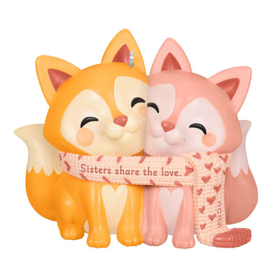 2025 Christmas ornament with two foxes snuggled in a heart-patterned scarf, celebrating sisterly love


