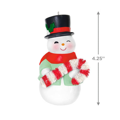 Porcelain snowman ornament in festive coat, scarf, and top hat holding a bottlebrush candy cane
