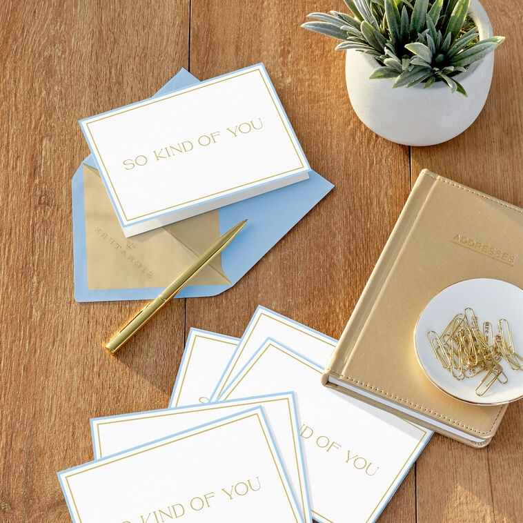 Elegant white thank-you cards with gold foil lettering, light blue border, and narrow gold frame.
