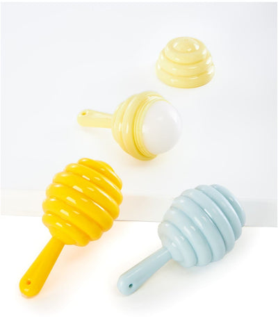 A 5g honey spoon–shaped lip balm in cream, blue, or yellow, packaged on a floral blister card; available in three nature.

