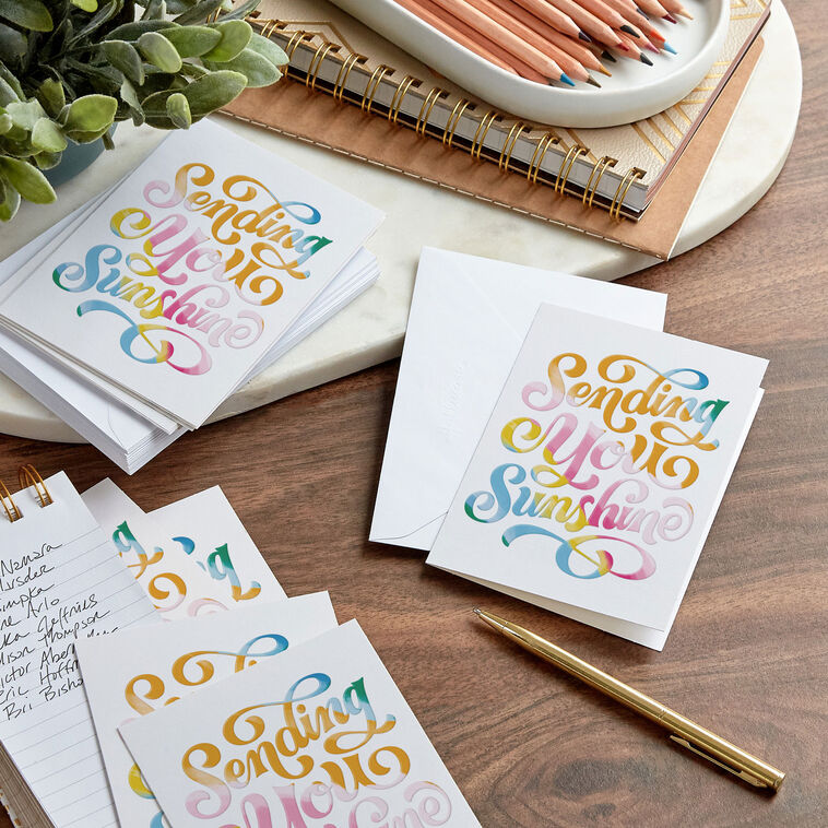 White blank note cards with colorful embossed “Sending You Sunshine” lettering in pink, orange, yellow, blue, and green.
