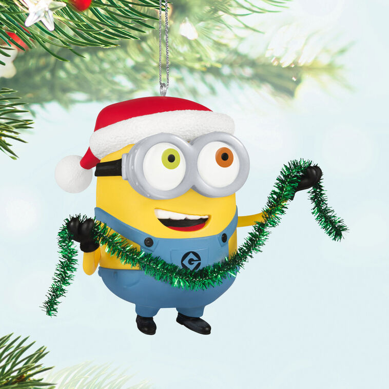Minion Bob ornament in Santa hat holding green tinsel garland with a big smile