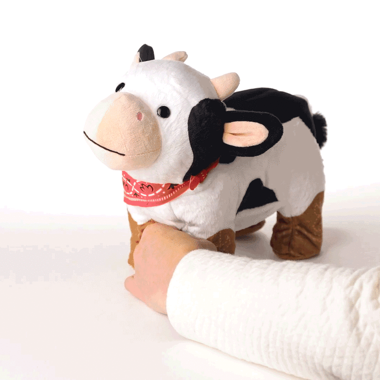 Spotted cow plush toy wearing red bandana and cowboy boots, dancing to &