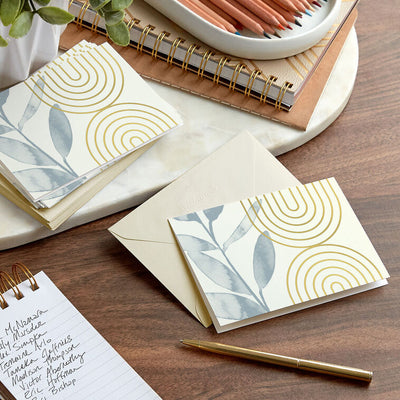 Ivory blank note cards with blue-gray eucalyptus branch artwork and gold foil concentric arch accents.