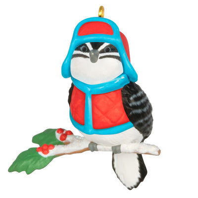 Miniature downy woodpecker ornament in red vest and trapper hat on snowy branch with holly berries, Hallmark Cozy Lil’ Critters
