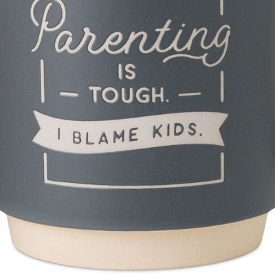 Blue-gray ceramic mug with white banner that reads “Parenting is tough. I blame kids,” oversized handle and stackable base.