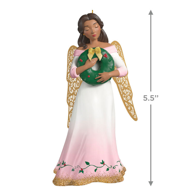 Hallmark Keepsake ornament of angel in pink and white gown with holly vines, holding a green wreath, gold metal wings, glitter accents