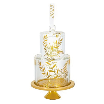 Glass wedding cake ornament with gold leaf and floral accents on clear tiers, featuring “2025” and gold base for newlywed Christmas keepsake.