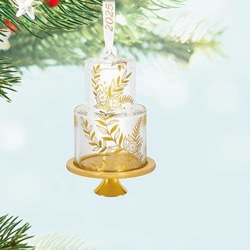 Glass wedding cake ornament with gold leaf and floral accents on clear tiers, featuring “2025” and gold base for newlywed Christmas keepsake.