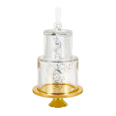 Glass wedding cake ornament with gold leaf and floral accents on clear tiers, featuring “2025” and gold base for newlywed Christmas keepsake.