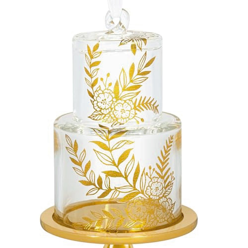 Glass wedding cake ornament with gold leaf and floral accents on clear tiers, featuring “2025” and gold base for newlywed Christmas keepsake.