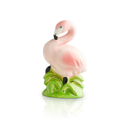 Pink flamingo statue sitting on a green plant