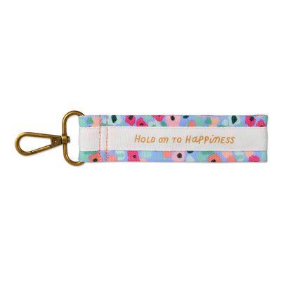 Hallmark floral wrist strap key ring with carabiner clip and “Hold on to happiness” message in pink script.