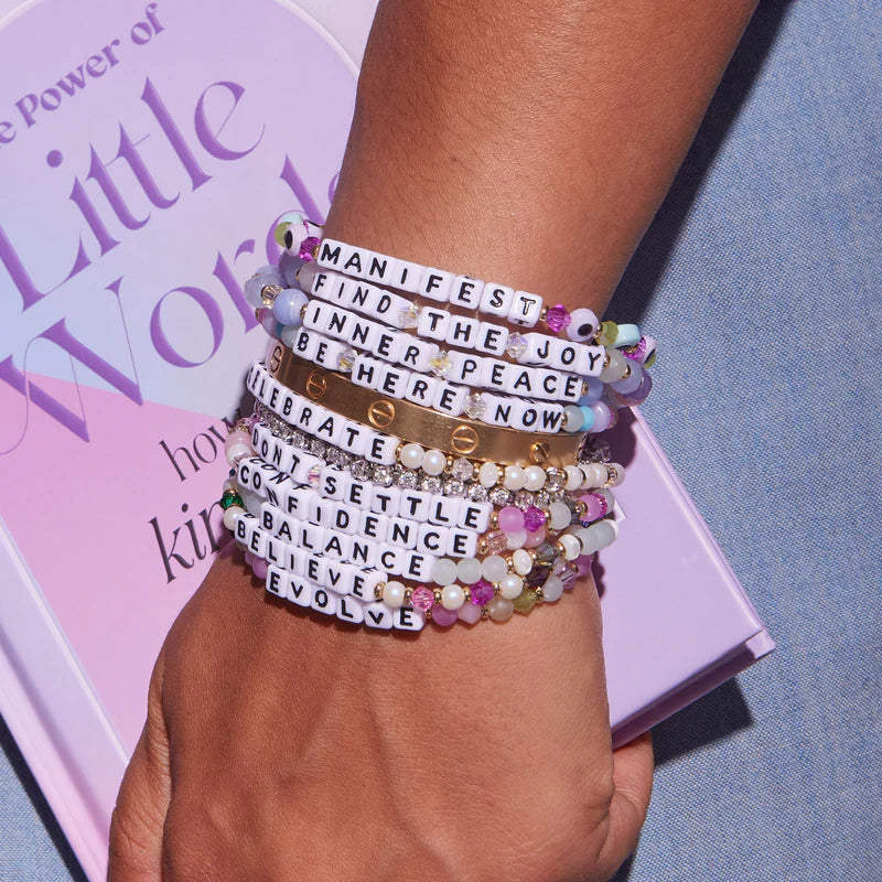 Medium/large beaded bracelet with pearl, crystal, and glass accents featuring Evolve in white and gold letter beads.

