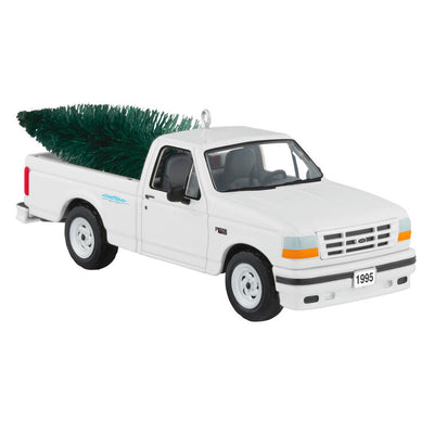 White 1995 Ford SVT Lightning truck ornament with turning wheels and a green bottlebrush Christmas tree in the truck bed.