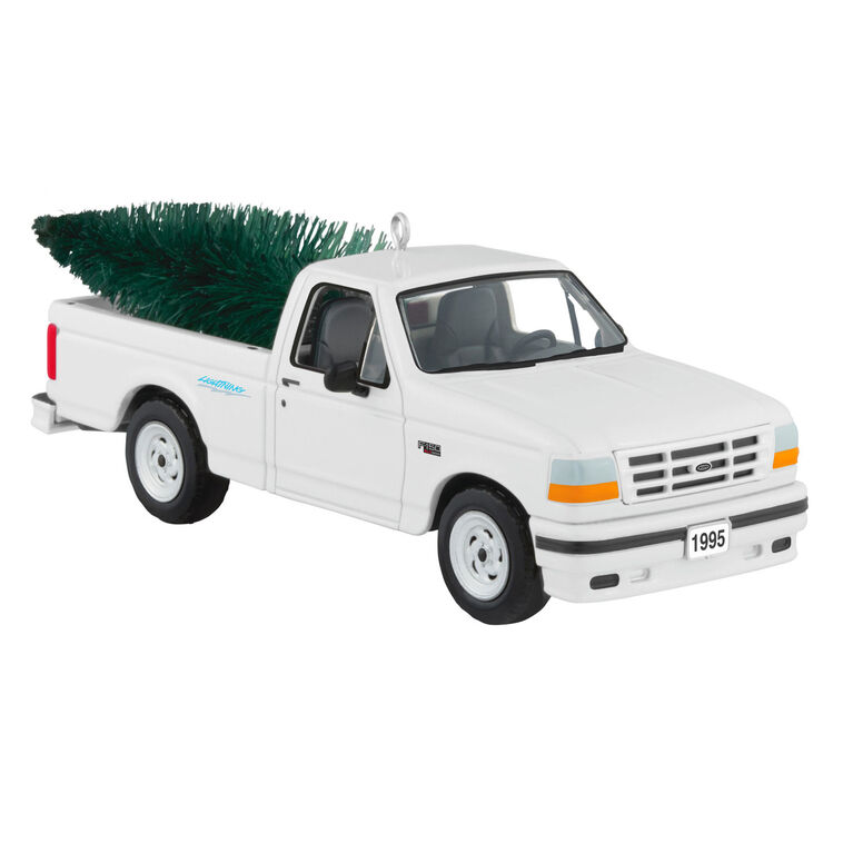 White 1995 Ford SVT Lightning truck ornament with turning wheels and a green bottlebrush Christmas tree in the truck bed.