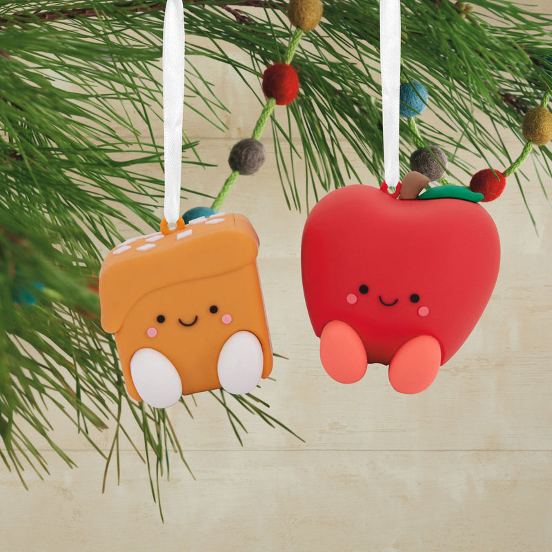 Two Hallmark magnetic Christmas ornaments: a red apple and a slice of bread with a smiley face. 