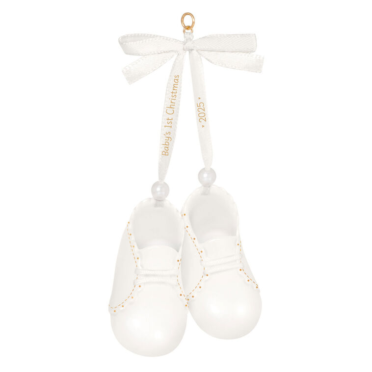 White porcelain baby booties ornament with 14K gold accents and satin ribbon bow, marked for baby’s 1st Christmas 2025.