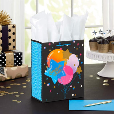 Hallmark medium graduation gift bag with colorful balloon bouquet, gold confetti accents, and "Congrats Grad!" message.

