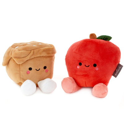 Two plush apples with attached leaves. One apple is red and one is green. They are connected by a brown fabric vine.