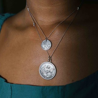 a silver necklace with a round medallion pendant . Text in the bottom right corner reads “ARCHANGEL RAPHAEL.”
