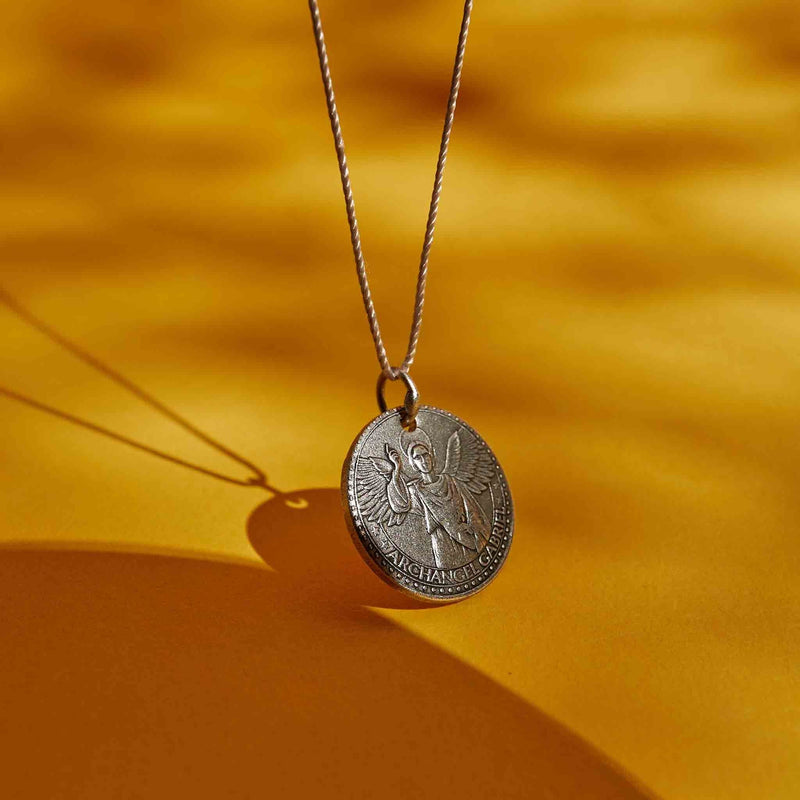 a siliver vermeil necklace with a round medallion pendant. The text “ARCHANGEL GABRIEL” is engraved around the edge of the medallion.