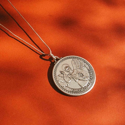 a siliver vermeil necklace with a round medallion pendant. The text “ARCHANGEL GABRIEL” is engraved around the edge of the medallion.