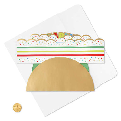 Hallmark 3D pop-up birthday cake paper decor with rainbow stripes, sprinkles, gold foil accents, and "Happy Birthday" banner.

