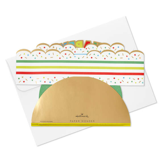 Hallmark 3D pop-up birthday cake paper decor with rainbow stripes, sprinkles, gold foil accents, and "Happy Birthday" banner.

