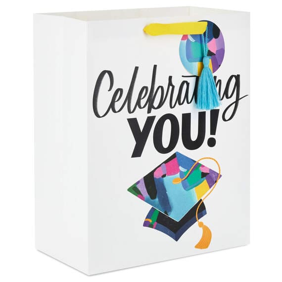 Hallmark large graduation gift bag with colorful mortarboard, black lettering on white, gift tag, and tassel attachment.

