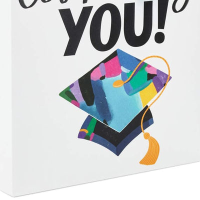 Hallmark large graduation gift bag with colorful mortarboard, black lettering on white, gift tag, and tassel attachment.

