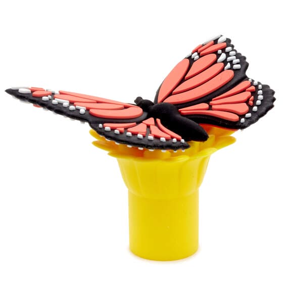 Image of a butterfly resting on a yellow tube. The butterfly has orange wings with black 