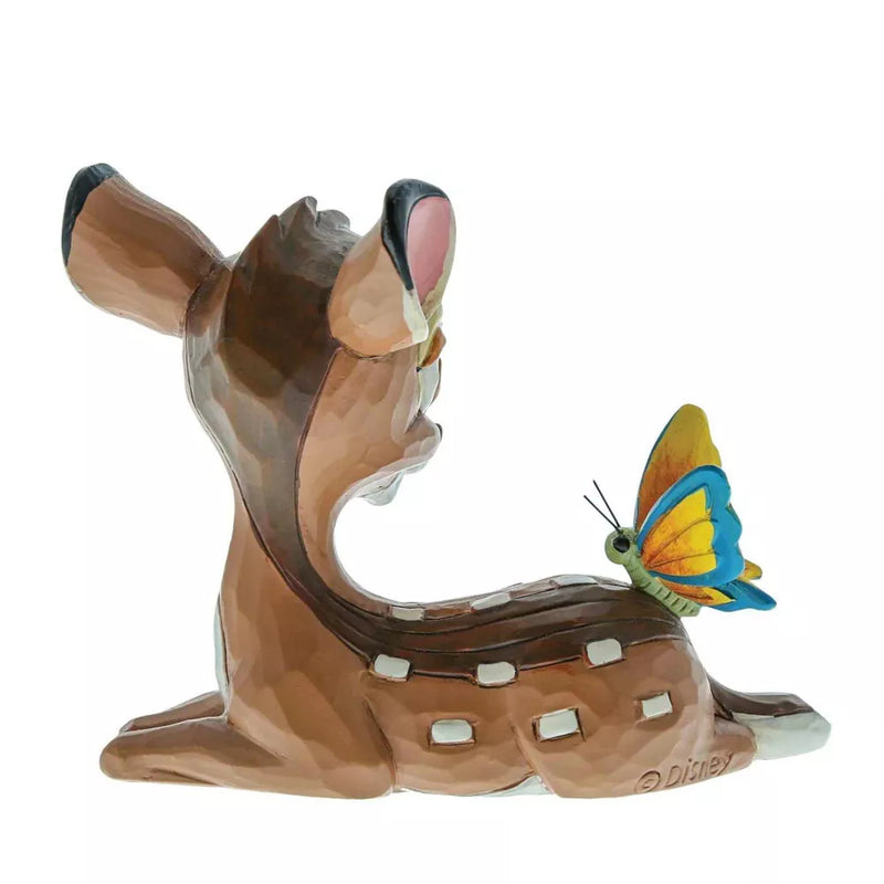 A cream colored ceramic figurine of a deer with a butterfly on its back