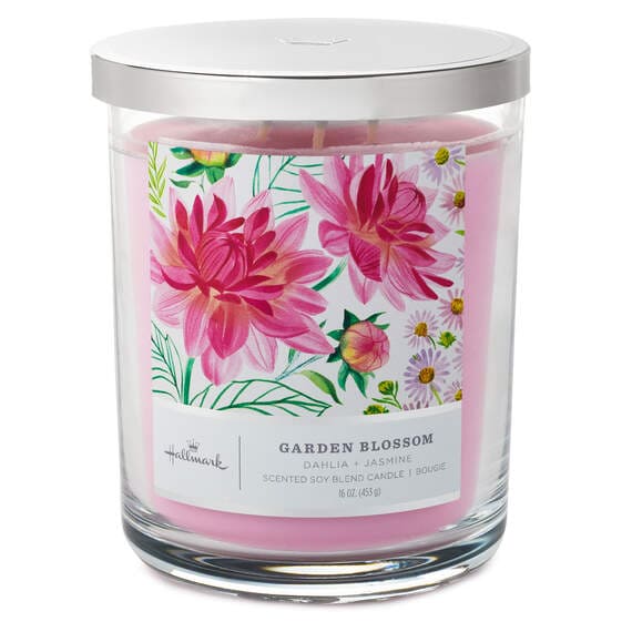 Glass jar with a pink wax seal labeled “Hallmark Garden Blossom”  filled with pink flowers and a soy blend candle. The candle wick is white.  pen_spark     tune  share   more_vert